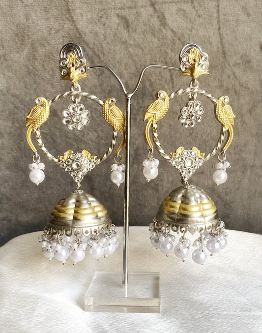 Pair of gold and silver earrings with pearl-like beads on a gray background