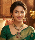 Woman wearing traditional jewelry and a green saree in an elegant setting